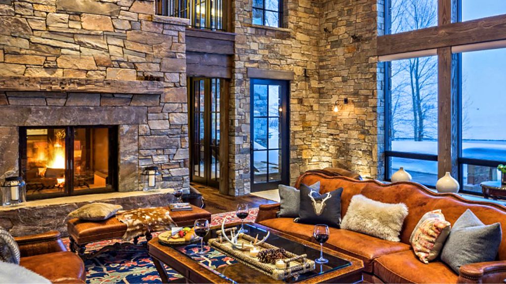 A cozy setting in a living room with window views and a fire going in a fireplace