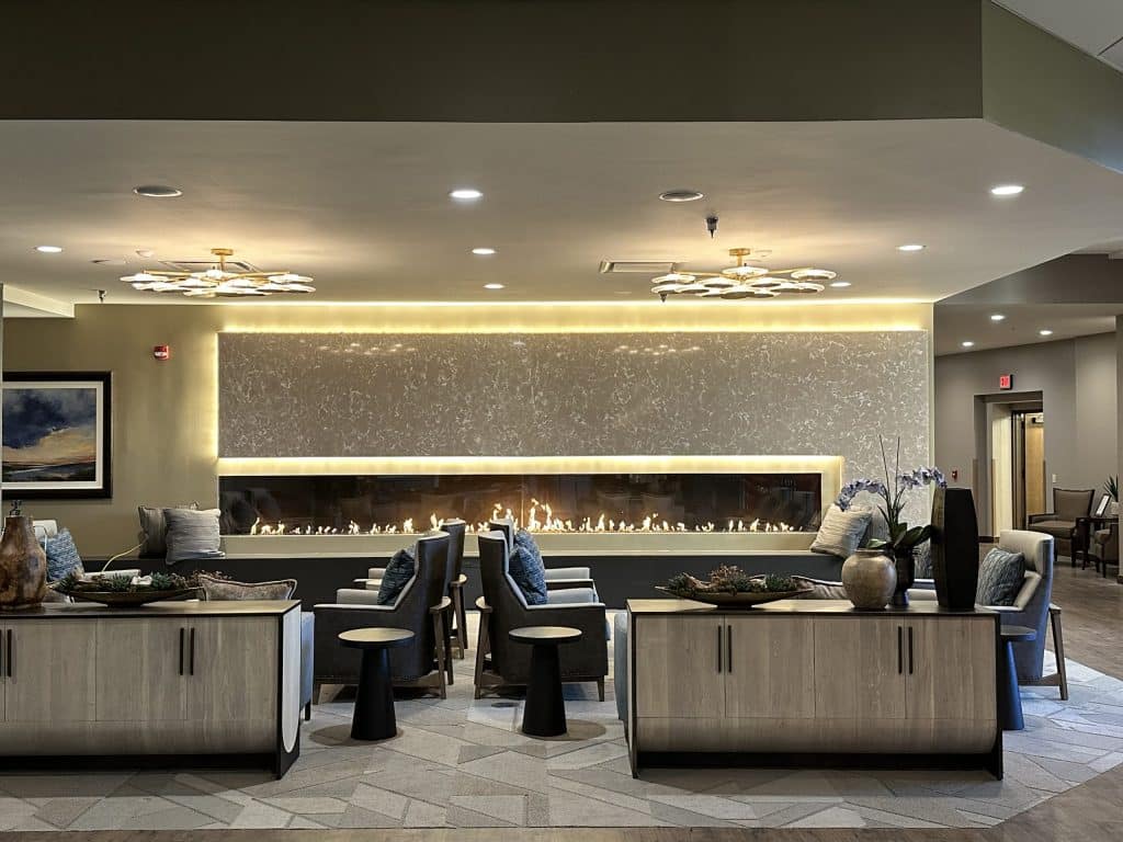 Acucraft Custom Single Sided 20' Linear Gas Fireplace Luxurious commercial lounge featuring a custom linear gas fireplace by Acucraft with glass media and ambient backlighting